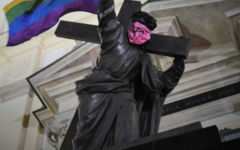 Jesus Monument Desecrated with LGBTQ Rainbow Flag & Anarchist Symbol Mask in Poland